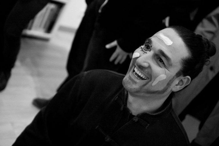 Foto retrato del actor Antonio Valls sonriendo y con la cara pintada con rayas blancas y un ojo con pestañas y patillas prolongadas