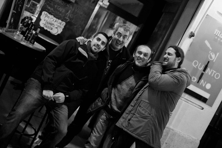 Foto de grupo de amigos de Totart en una bar con el cartel y la barra de fondo