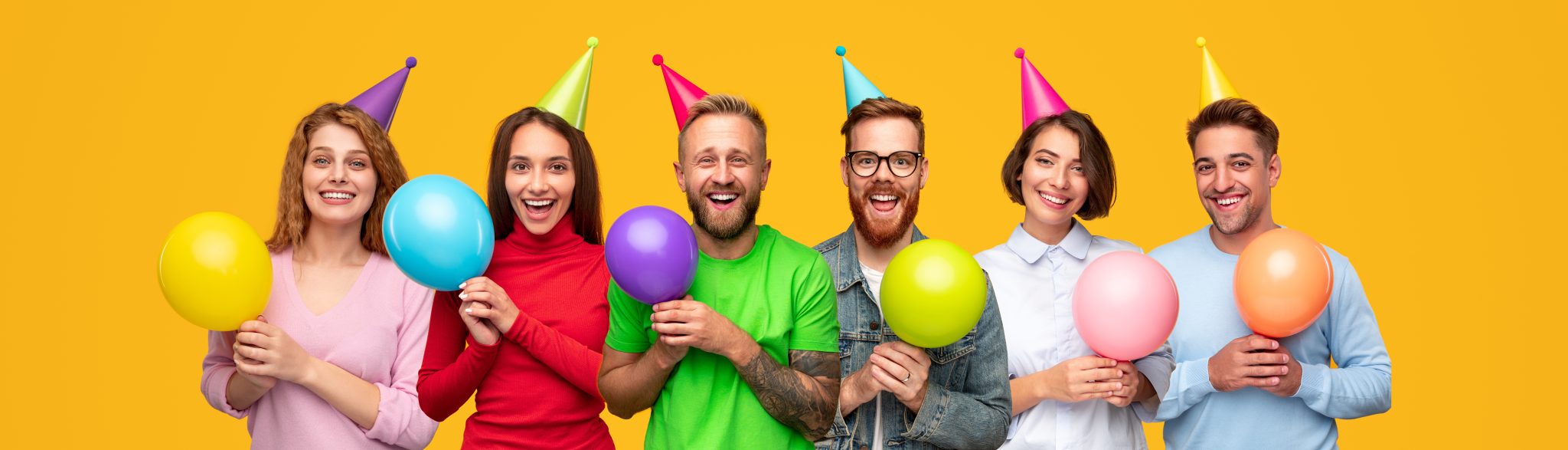 Adultos con gorros y globos de diferentes colores celebrando un evento