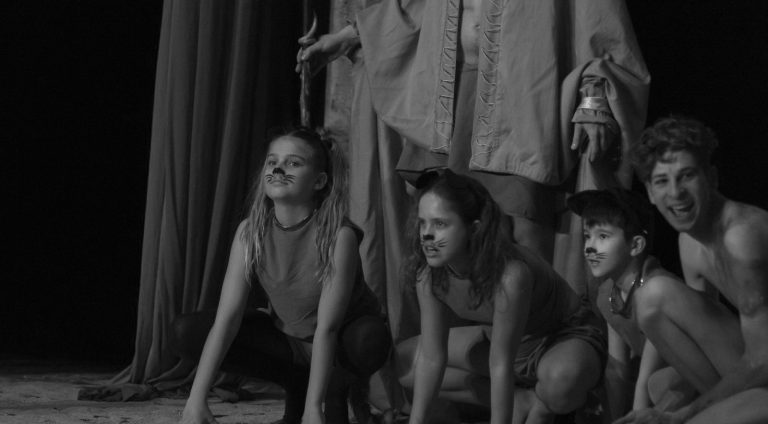 Niños y adultos interpretando en una representación de una obra teatral. Los niños perritos y los adultos amo y sirviente del aire