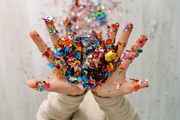 Manos de una niña tirando confeti de diferentes colores al finalizar su actuación