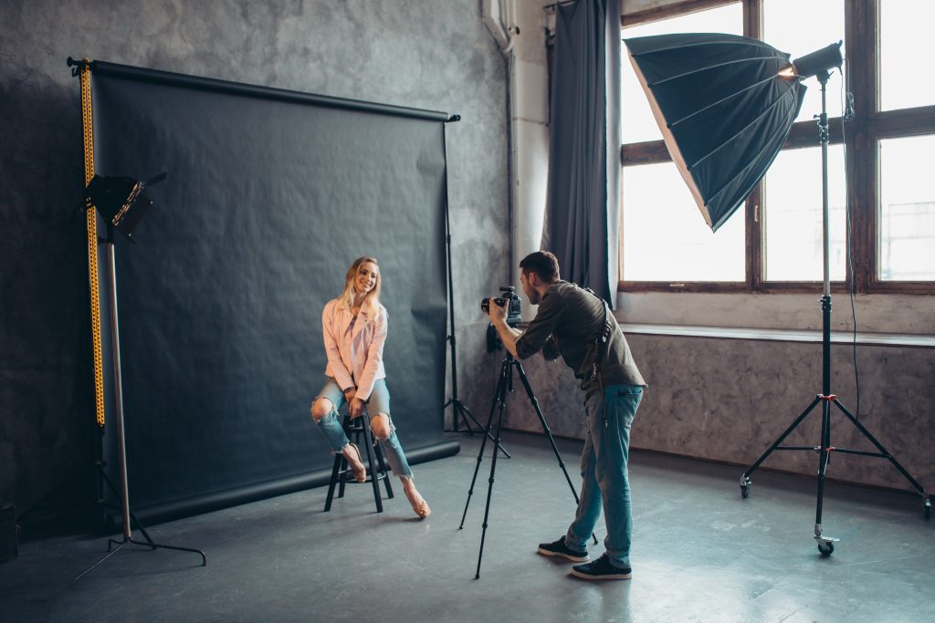 Actriz posando para fotógrafo en interior junto a las luces y fondo negro
